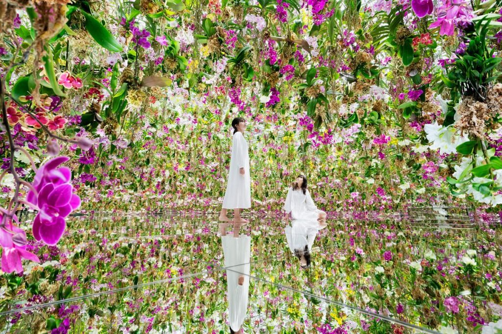 Interior de museu imersivo com arte digital interativa, flores que brilham ao toque dos visitantes