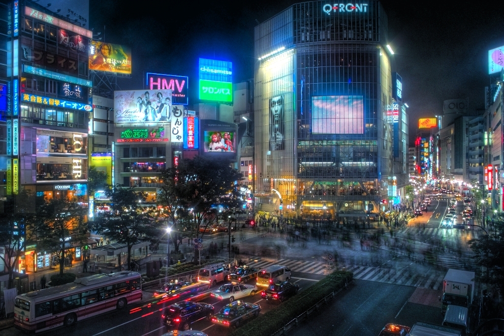 Cruzamento de Shibuya à noite com letreiros luminosos em Tóquio